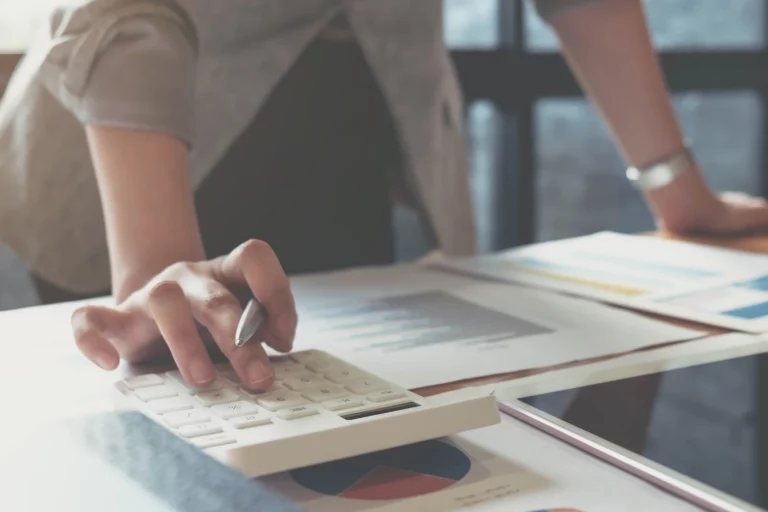Woman's hands on a calculator with documents next to it